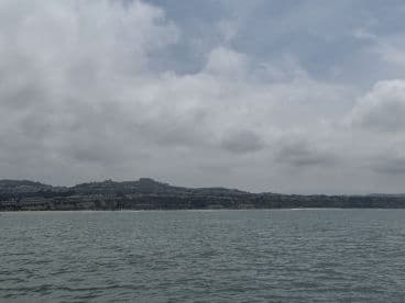 A distant view of a coastal landscape with cloudy skies, lacking clear focus or identifiable features.