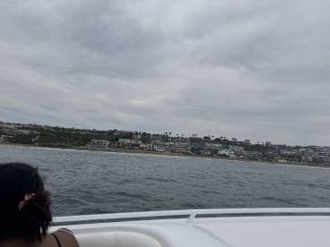 A scenic view of coastal homes from a boat, showcasing the beautiful shoreline and cloudy skies — perfect for a relaxing day on the water.