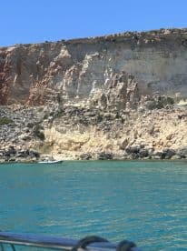 A scenic view of a coastline with a small boat navigating the turquoise waters, perfect for island hopping adventures.