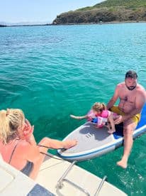 A family enjoys a fun day on the water, with a child and adult paddleboarding in the clear turquoise sea — perfect for creating lasting memories on a summer adventure.