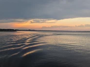 A serene sunset over calm waters, showcasing beautiful reflections and a tranquil atmosphere — perfect for capturing the essence of a peaceful evening on the water.