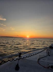 A serene sunset view from the deck of a boat, showcasing the tranquil waters and vibrant colors of the sky — perfect for evening cruises.