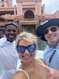 A cheerful group takes a selfie on a boat, capturing a fun moment against the backdrop of a stunning architectural feature — perfect for memorable outings and celebrations on the water.