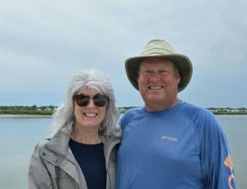 A cheerful couple poses for a photo by the water, capturing a moment of joy and connection during their boating adventure.