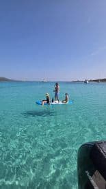 A fun day on the water with a group paddleboarding in crystal-clear waters, perfect for family adventures and water sports.