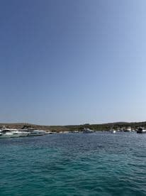 A picturesque view of a harbor filled with various boats, showcasing the serene turquoise waters and the surrounding landscape — perfect for boating enthusiasts and travelers seeking scenic destinations.