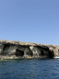 A stunning view of rocky caves along the coastline, with a boat anchored nearby, perfect for exploring hidden gems and enjoying the beauty of nature.