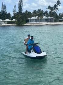 Two individuals enjoy an exciting jet ski ride in clear turquoise waters, showcasing the thrill of water sports in a tropical paradise.