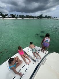 A group of children enjoys a fun day on the water, leaning over the side of a boat to explore the clear turquoise sea — perfect for family adventures and water activities.