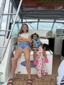 A cheerful moment captured inside a boat, featuring a teenager and a young child enjoying their time together in a cozy cabin setting.