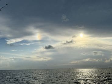 A stunning view of the ocean at sunset, showcasing dramatic clouds and reflections on the water — a perfect backdrop for a serene boating experience.