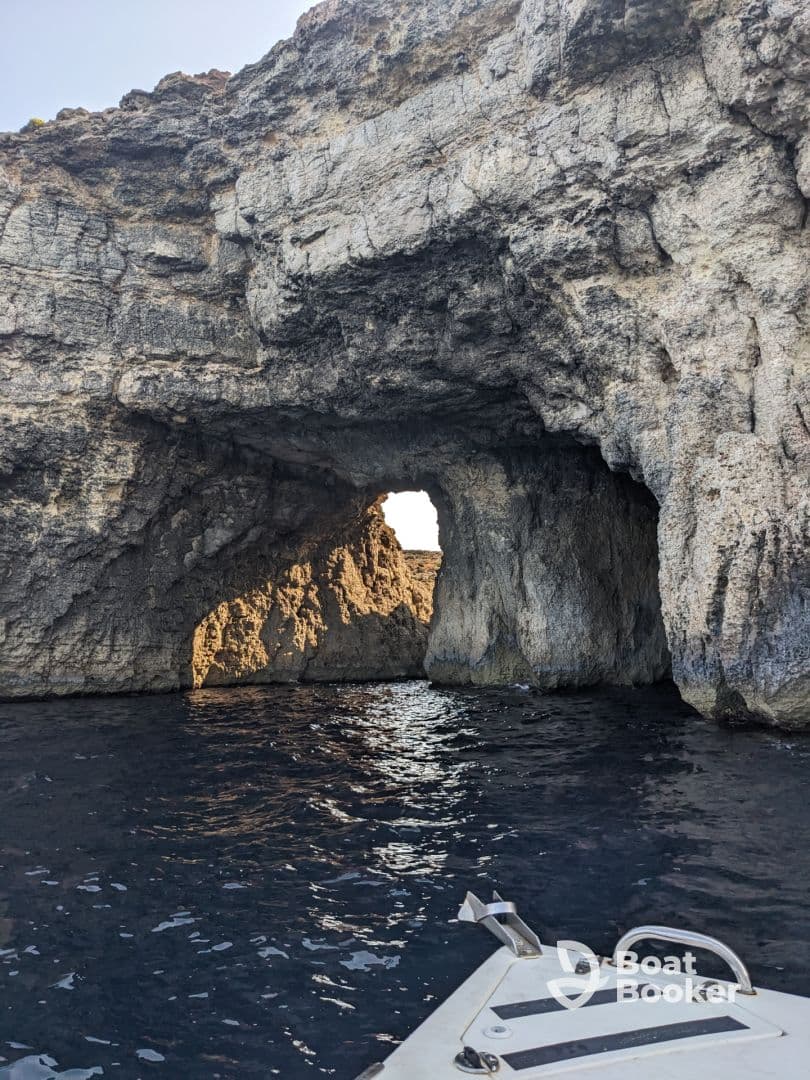 A stunning view of a natural rock formation with an arch, seen from a boat, showcasing the beautiful coastline and inviting waters perfect for exploration.