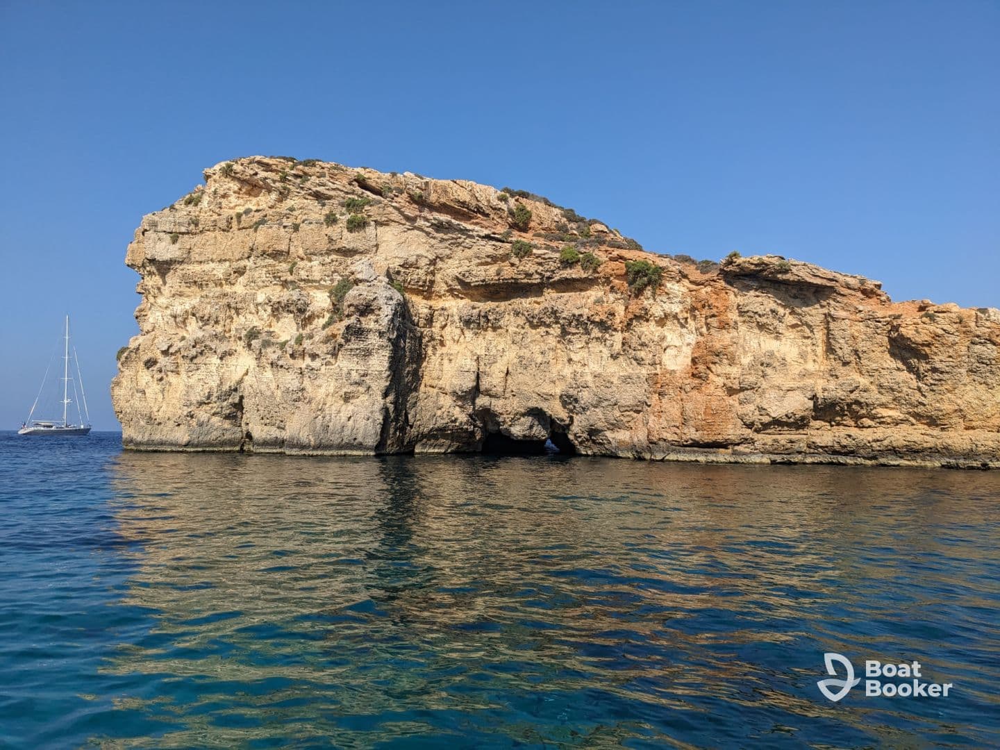 A stunning view of a rocky coastline with a sailboat in the distance, perfect for showcasing the natural beauty of sailing adventures.