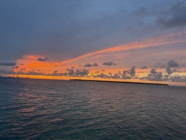 A breathtaking sunset over the coastline, showcasing vibrant colors reflecting on the water — a perfect backdrop for evening boat cruises.