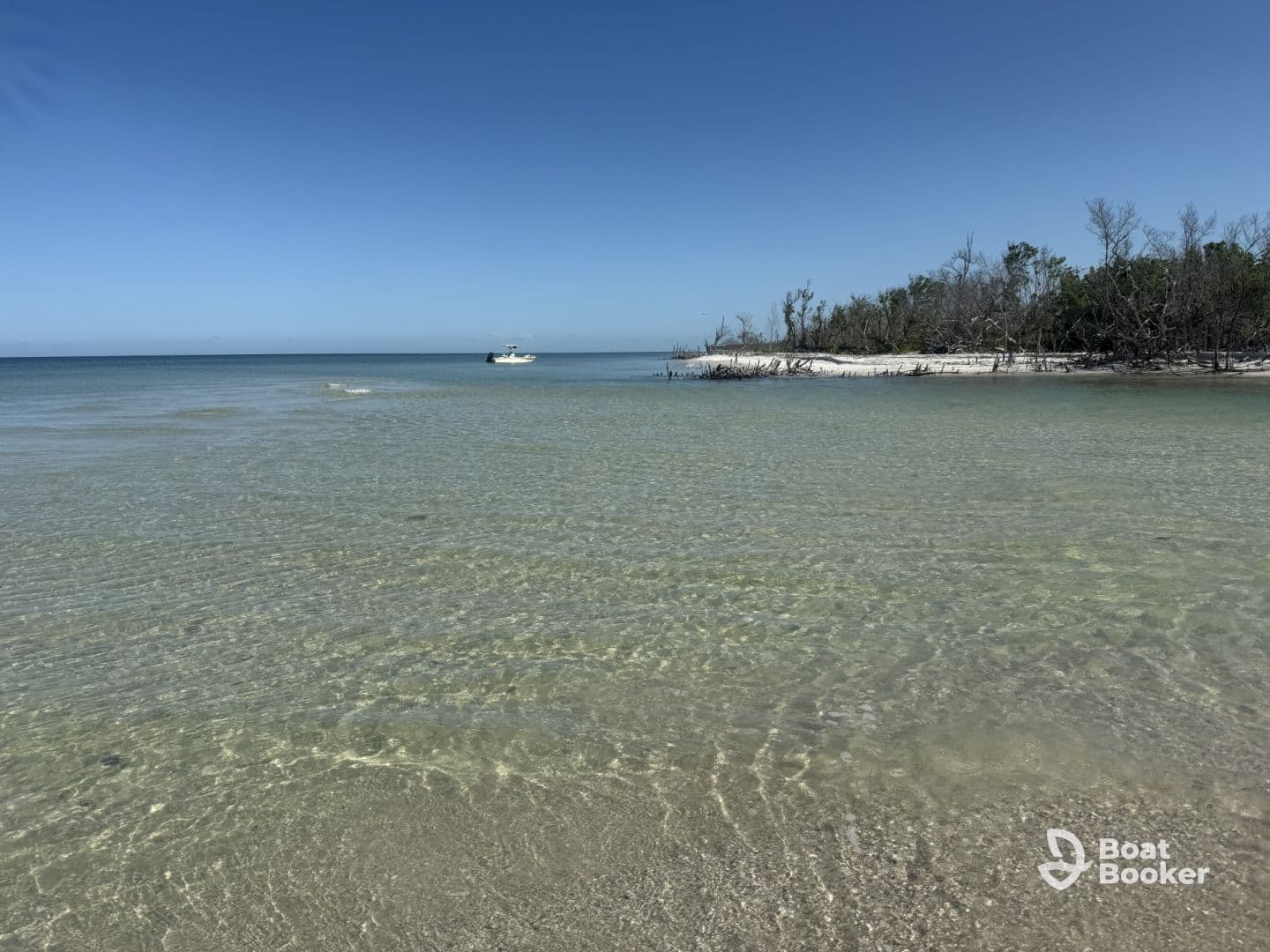 A serene view of a clear coastline with a boat anchored in the distance, showcasing the beauty of a tranquil beach setting.