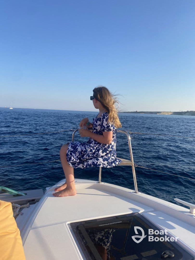 A young girl enjoys the ocean breeze while sitting on the bow of a boat, capturing the essence of a perfect sailing adventure.