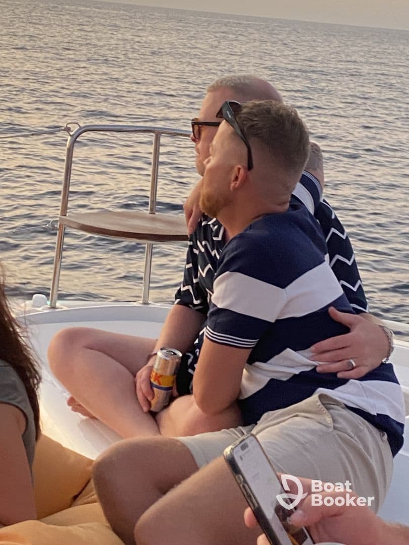 A couple enjoys a romantic moment on a boat, embracing as they take in the serene sunset views — perfect for intimate sunset cruises.