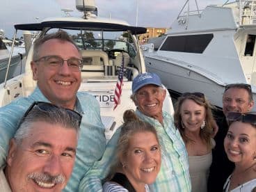 A cheerful group of friends poses for a selfie aboard a boat, capturing a moment of joy and camaraderie at the marina.