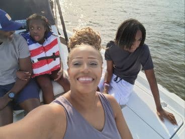 A joyful family enjoys a day on the water, capturing a fun moment aboard a boat with smiles and life jackets, perfect for summer adventures.