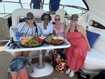 A group of friends enjoys a vibrant spread of fresh fruit and snacks aboard a luxurious boat, perfect for a relaxing day on the water.