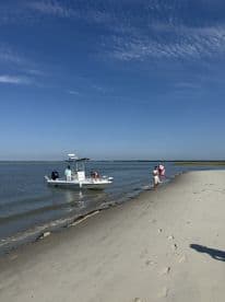 A group enjoys a day at the beach with a boat anchored nearby, perfect for swimming and relaxation in the sun.