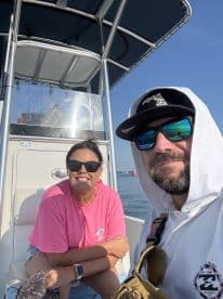 A cheerful couple enjoys a sunny day on their boat, capturing a moment of relaxation and fun on the water.