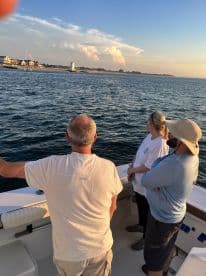 A group of friends enjoys the scenic view from their boat, taking in the sunset and coastal landscape — a perfect moment for relaxation and camaraderie on the water.
