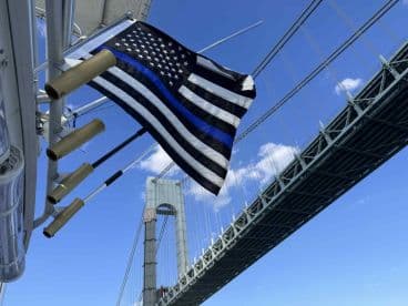 A striking view of a flag flying on a boat with a bridge in the background, showcasing the beauty of maritime journeys.