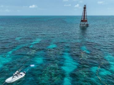 A scenic view of a boat near a snorkeling area, with guests enjoying water activities in the vibrant turquoise waters — perfect for adventure seekers exploring marine life.