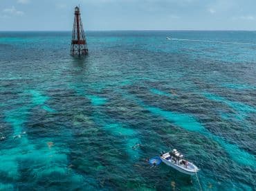 A vibrant scene of a boat anchored near a snorkeling spot, with people enjoying the clear waters and colorful marine life — perfect for adventure seekers.