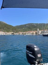 A scenic view from a boat showcasing a picturesque harbor surrounded by mountains, perfect for exploring coastal destinations.