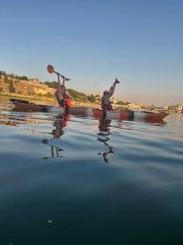 Two friends enjoy a fun kayaking adventure, paddling in sync on calm waters — a perfect way to explore scenic waterways.