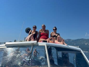 A fun group of friends relaxes on the bow of a boat, enjoying the sun and the beautiful scenery — perfect for a day out on the water.