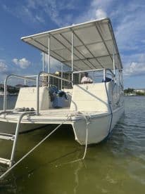 A catamaran is docked with a person visible on board, showcasing its spacious design and inviting atmosphere for water adventures.