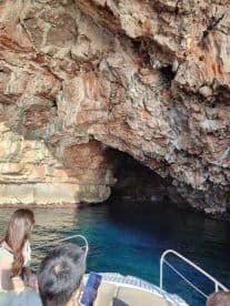 Guests explore a stunning cave while boating, surrounded by vibrant rock formations and clear waters — a perfect adventure for nature lovers.