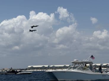 An exciting airshow featuring fighter jets flying above a gathering of boats, showcasing a thrilling day on the water with friends and family.