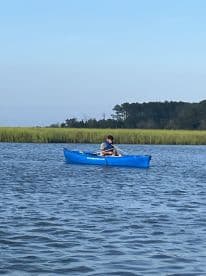 Two individuals enjoy a peaceful kayaking experience in calm waters, surrounded by lush greenery — a perfect way to explore nature.