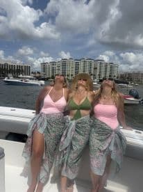 Three friends enjoy a sunny day on the water, soaking up the sun and celebrating together on a boat — perfect for summer outings and memorable moments.