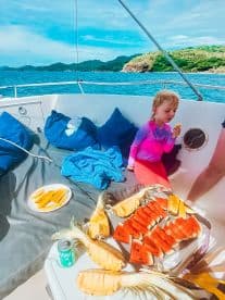 A delightful spread of fresh fruit, including watermelon and pineapple, enjoyed by a child on a boat — perfect for a refreshing snack while cruising the waters.