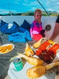 A child enjoys fresh fruit snacks aboard a boat, featuring a colorful spread of watermelon and pineapple, perfect for a refreshing day on the water.