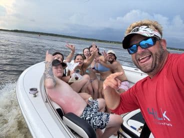 A lively group of friends enjoys a fun day on the water, celebrating together aboard a boat. Perfect for capturing the essence of summer adventures and memorable outings.