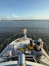 A group enjoys a sunny day on the bow of a boat, showcasing a relaxed atmosphere perfect for summer outings on the water.
