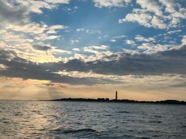 A stunning sunset view featuring a lighthouse along the coastline, capturing the serene beauty of the water and sky — perfect for nature lovers and photography enthusiasts.