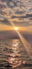 A stunning sunset over calm waters, showcasing the beautiful reflections and serene atmosphere perfect for evening boat cruises.