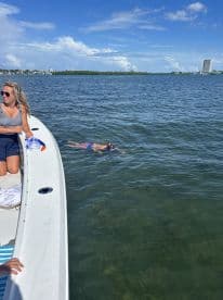 A lively scene featuring a group enjoying snorkeling off the side of a boat, with a child swimming nearby — a perfect day for aquatic adventures.