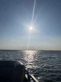 A serene view of the sun shining over the water, with a glimpse of the boat's seating, perfect for capturing the tranquility of a day on the water.