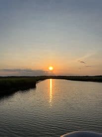 A serene sunset over a tranquil waterway, reflecting golden hues on the surface — perfect for peaceful evening boat rides.