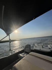 A serene view of the interior of a boat, showcasing comfortable seating and a helm under a shaded canopy, perfect for enjoying a day on the water.