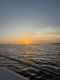 A serene sunset view over calm waters, captured from the deck of a boat, creating a perfect backdrop for evening cruises.
