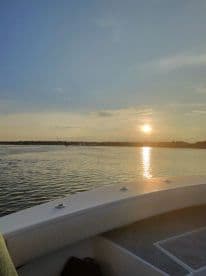 A serene sunset view from the deck of a boat, showcasing tranquil waters and a picturesque horizon — perfect for evening cruises.